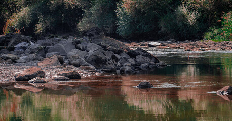 Reflected of rocks and trees on the river in autumn.