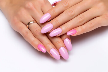 Gel. Pink manicure with pink sequins on long oval nails close-up on a white background.