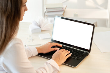 Fototapeta premium Distance work. Freelance workplace. Business communication. Woman in white shirt typing on laptop blank screen modern light interior copy space.