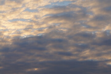 Clouds in the blue sky in the evening, during autumn, warm colours - background.