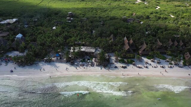 Sobre Tulum Beach con una vista a&eacute;rea a la nutrida vegetaci&oacute;n de la zona y algunas personas caminando sobre la playa.