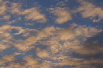 Clouds in the blue sky in the evening, during autumn, warm colours - background.