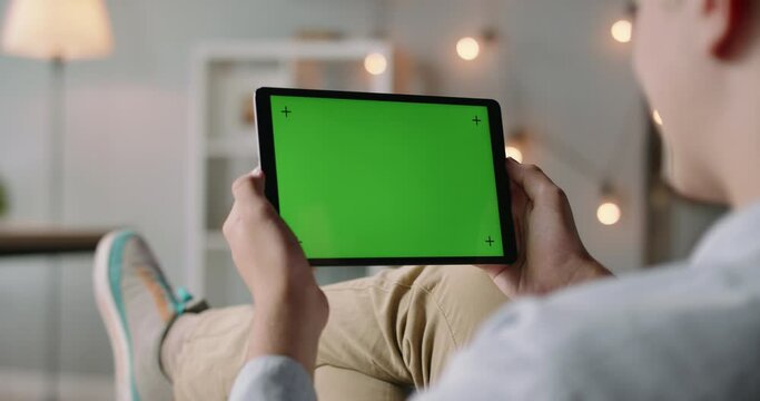Guy having video chat with relatives or colleagues. Close-up shot of caucasian man holding a tablet with green mock up chroma key screen 4k footage