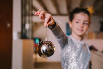 Horizontal view of unrecognizable little girl holding a spherical Christmas ornament to hang from a...