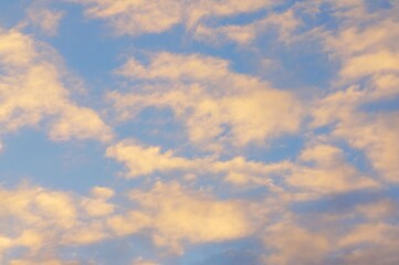Clouds in the blue sky in the evening, during autumn, warm colours - background.