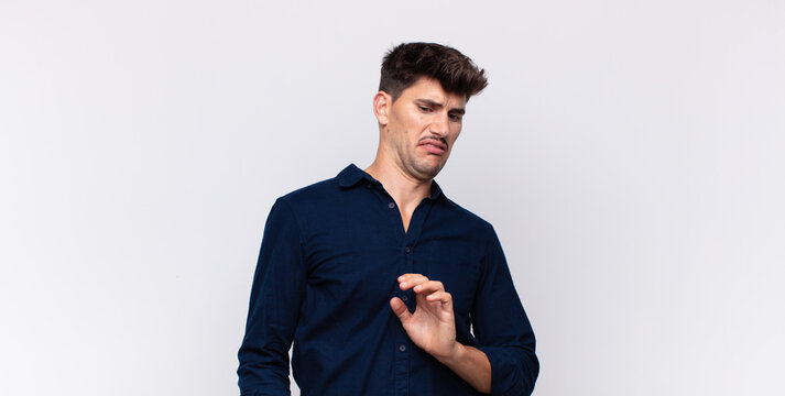 young handsome man feeling disgusted and nauseous, backing away from something nasty, smelly or stinky, saying yuck
