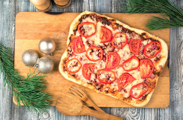 Christmas table with pizza and pine branches on a wooden background. The view from the top. The concept of New year and Christmas.