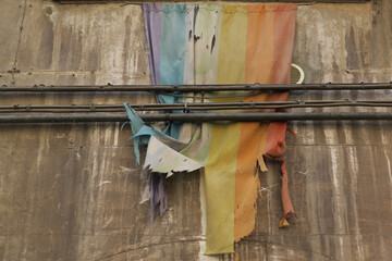 damaged rainbow flag hanging on an old wall in Viterbo