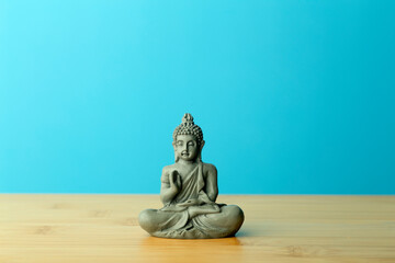 Zen, meditation and relaxation background. Buddha figurine on an empty calm blue background.