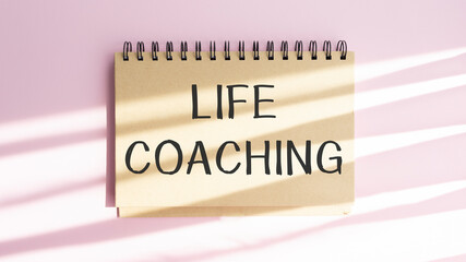 Note with words life coach on a pink background.