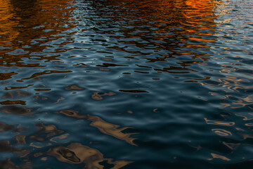 Orange red reflections in blue water. Ships, rusty barges in the light of the sunset