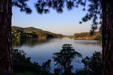 Paisagem de represa no pôr do sol, final de tarde, com ar bucólico e tranquilo.