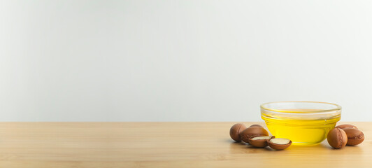Argan oil banner background. Argan nuts  and oil on a wooden table on a empty white background. Copy space