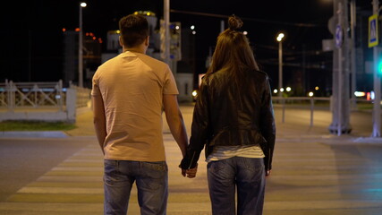 Couple holding hand walking along the pedestrian road in the evening
