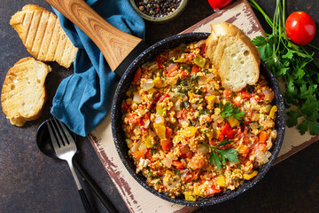 Turkish cuisine. Menemen Scrambled eggs in a cast iron frying pan on a stone countertop. Top view flat lay background. - obrazy, fototapety, plakaty