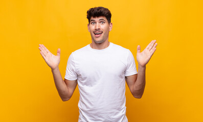 young handsome man feeling happy, excited, surprised or shocked, smiling and astonished at...