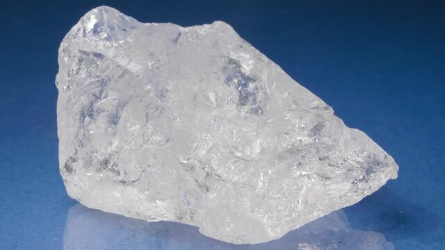 Mineral rock crystal on a blue background. Colorless quartz close-up view.