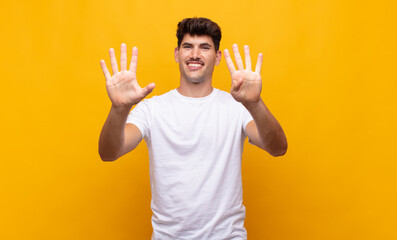 young handsome man smiling and looking friendly, showing number nine or ninth with hand forward,...