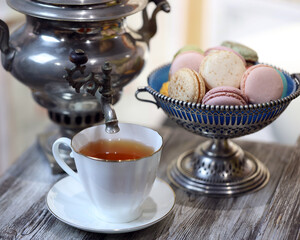 a cup of tea, macaroons and a samovar on the table