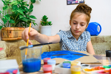 a girl drawing blue gouache cardboard, artistic creation at home, makes creative artwork