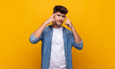 young handsome man looking concentrated and thinking hard on an idea, imagining a solution to a...
