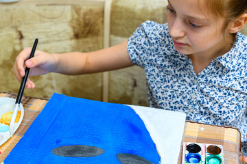 a girl drawing blue gouache cardboard, artistic creation at home, makes creative artwork