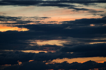 beautiful sunset sky, bright sun and dark silhouette of clouds as a background