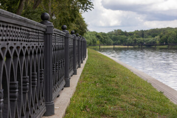 Railings of the embankment on the shore of the pond close up