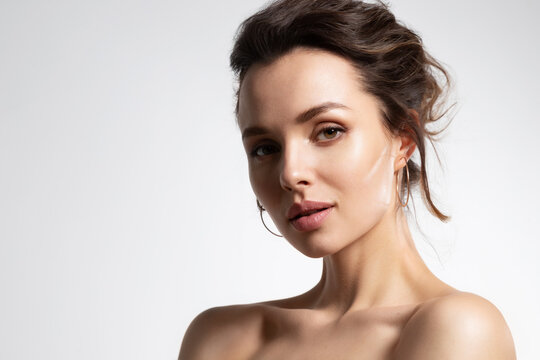 Close up of beautiful young woman with healthy soft glowing skin and bare shoulders in studio isolated on white background. Advertising poster for skincare cosmetics and rejuvenation procedure