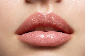 Close up of young woman wearing light fresh lip make up and slightly opening mouth. Plump lips with...