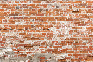 Weathered red brick wall, background with copy space for text. Texture or effect of old building, urban or loft style. Grunge facade for exterior. Rough surface with worn old stones and cracks