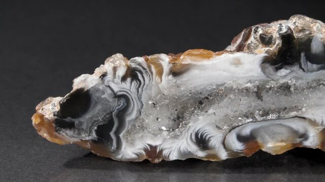 The agate close-up on a black background. A slice of mineral. Chalcedony, quartz on macro video. close-up
