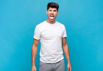 young handsome man with cheerful, carefree, rebellious attitude, joking and sticking tongue out,...