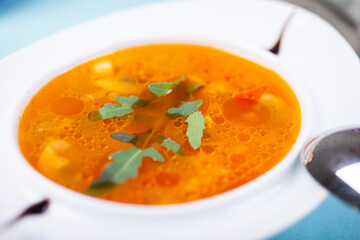 Traditional vegetable soup broth in a white plate on a table in a restaurant.