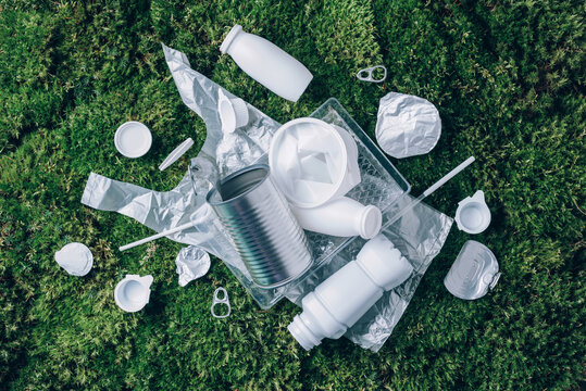 Plastic waste, food packaging, trash collection on green moss background after picnic in forest. Plastic free. Top view. Copy space. Recycling plastic. Environmental pollution, ecology concept.