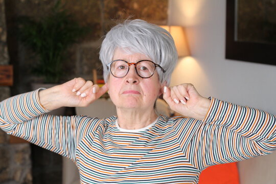 Stubborn Senior Woman Blocking Ears With Fingers 
