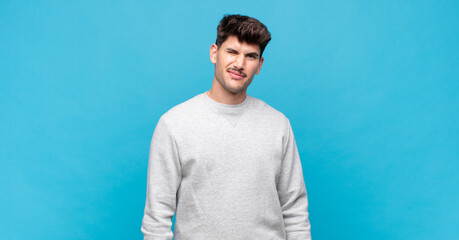 young handsome man looking happy and friendly, smiling and winking an eye at you with a positive...