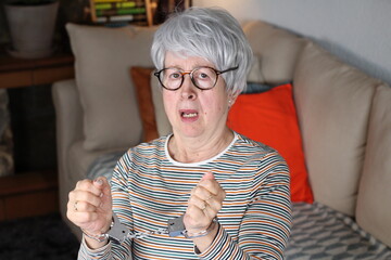 Handcuffed senior woman in the sofa
