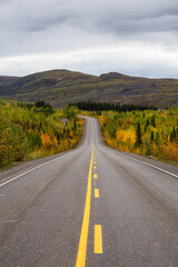 Fototapeta premium View of Scenic Road surrounded by Mountains and Trees on a Fall Day in Canadian Nature. Klondike Highway, Yukon, Canada.