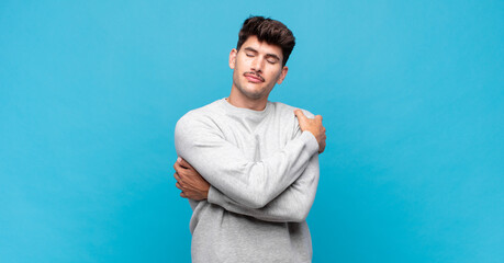 young handsome man feeling in love, smiling, cuddling and hugging self, staying single, being...