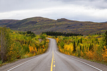 View of Scenic Road surrounded by Mountains and Trees on a Fall Day in Canadian Nature. Klondike Highway, Yukon, Canada.