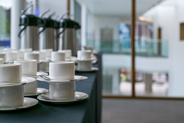 Stacks of white china coffee cups and saucers ready for morning breakout session at corporate...