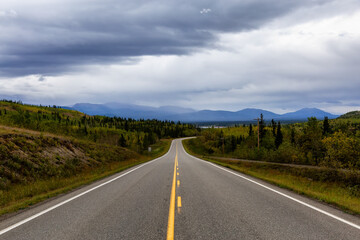 View of Scenic Road surrounded by Mountains and Trees on a Fall Day in Canadian Nature. Klondike Highway, Yukon, Canada.