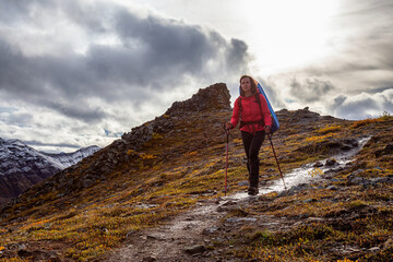Woman Backpacking along Scenic Hiking Trail surrounded by Mountains in Canadian Nature. Season...