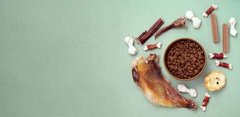 Dog delicacy food and feed in bowl on green background with copy space. Variety of dog treats.