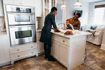 Young Black family prepares food in kitchen for holiday gathering