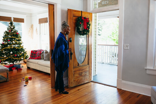 Senior woman welcoming visitors to home for Christmas