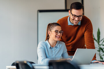Young businessman helping his female colleague in office