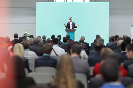 Man speaking on a pedestal on a conference in front of an audience
