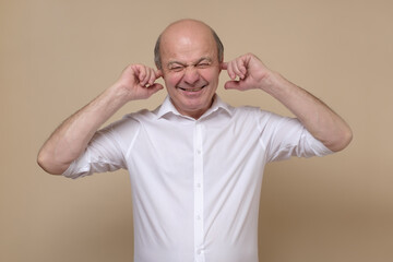 Senior caucasian man covering his ears trying to avoid hearing spoilers. Studio shot